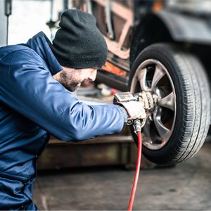 Man working on a vehicle wheel wearing coveralls