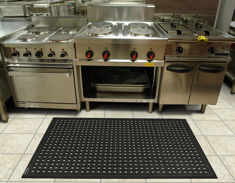 A restaurant kitchen with stainless steel appliances and a anti fatigue mat.