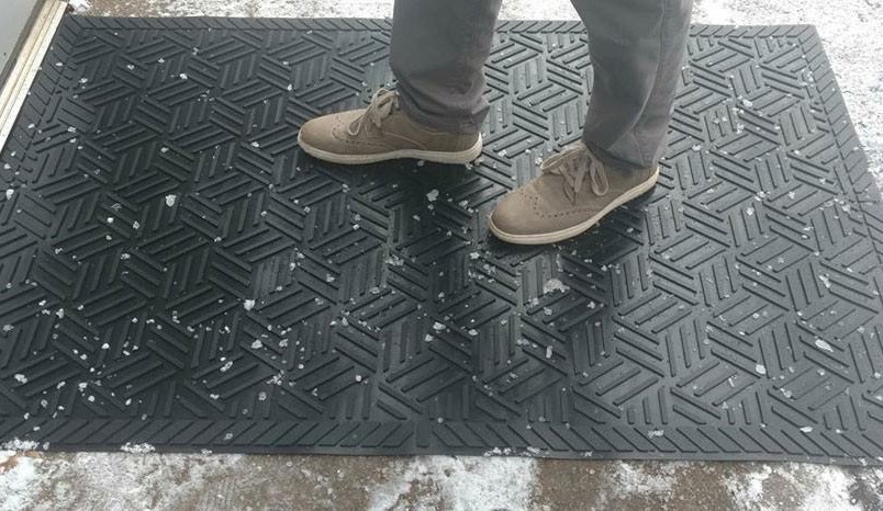 A person standing on a scraper mat.
