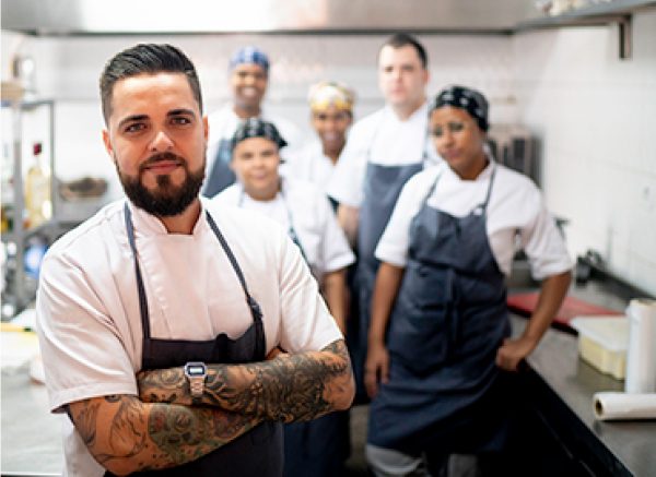 A group of kitchen staff wearing chef coats and aprons