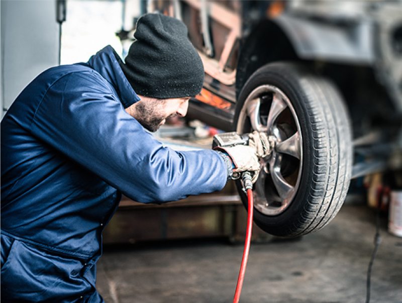 Man working on a vehicle wheel wearing coveralls