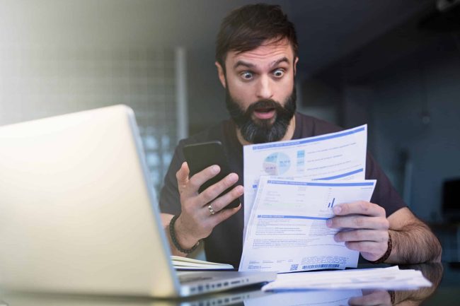 shocked-man-looks-at-phone-and-documents-2026-03-09-06-34-52-utc (1)